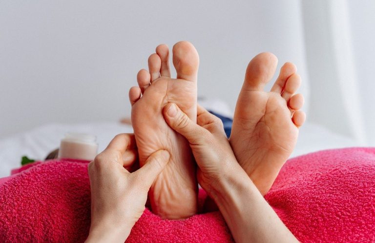 Deux pieds sur un coussin, massés par une main.